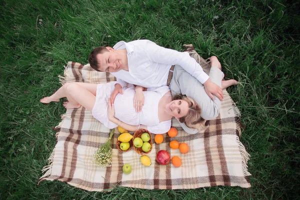 Gelukkige paar - zwangere vrouw en haar echtgenoot op een picknick op een zonnige dag — Stockfoto