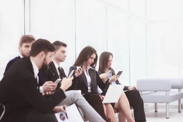 Equipo de negocios utiliza computadoras portátiles y teléfonos inteligentes mientras está sentado en el lobby de la oficina.Generación de estilo de vida de Internet — Foto de Stock