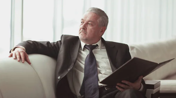 Nadenkend zakenman met zittend op de Bank van het office klembord — Stockfoto