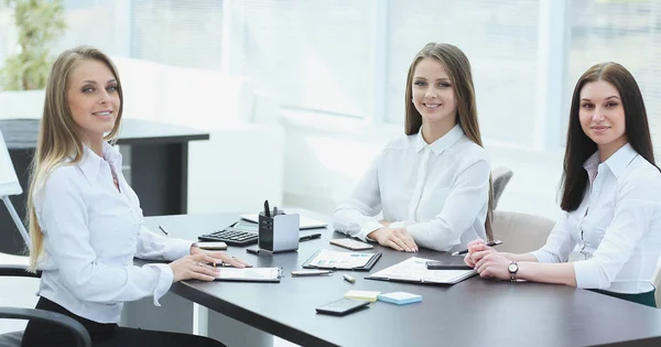 Tres jóvenes empleados sentados detrás de un escritorio — Foto de Stock