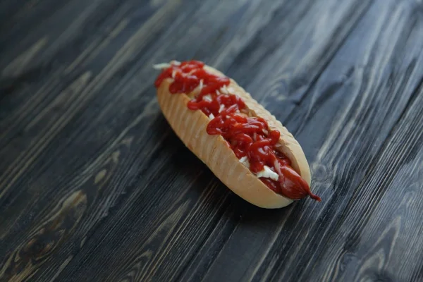 Hot dog with spicy sauce on dark background.photo with copy spac — Stock Photo, Image