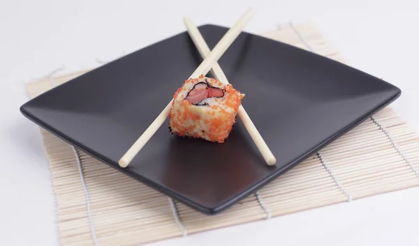 Close-up de sushi e pauzinhos em uma placa preta — Fotografia de Stock