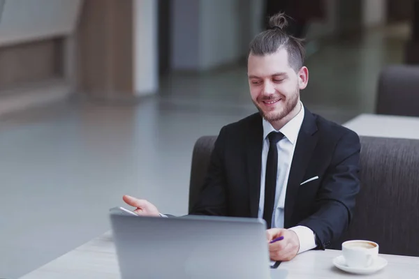 Närbild. glad affärsman sitter vid sitt skrivbord — Stockfoto