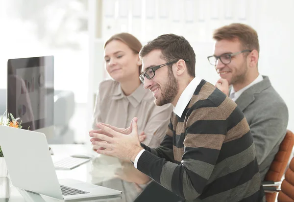 Sonriente equipo de negocios sentado en el escritorio —  Fotos de Stock