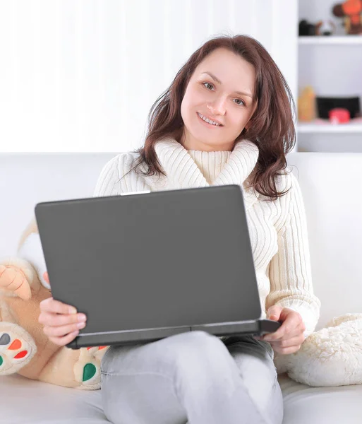 Moderna mor med laptop sitter i soffan i barnkammaren — Stockfoto