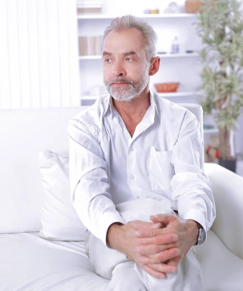 Serious businessman sitting on sofa in his office — Stock Photo, Image