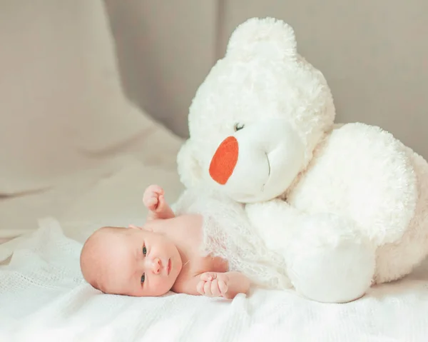 Retrato de un bebé recién nacido con un juguete suave en la cama de los padres — Foto de Stock