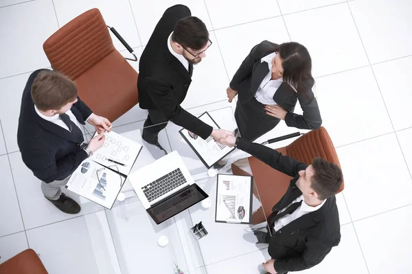 Top view.handshake ludzi biznesu na prace biurko — Zdjęcie stockowe
