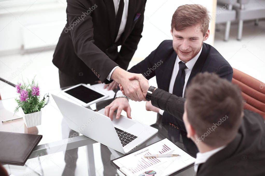 Managers and clients handshakes over the Desk in the Banks office