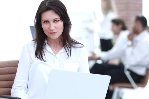 Femme d'affaires sérieuse avec ordinateur portable assis dans le hall du bureau — Photo