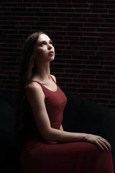 Kırmızı elbiseli bir sandalyede oturuyor şık genç kadın — Stok fotoğraf