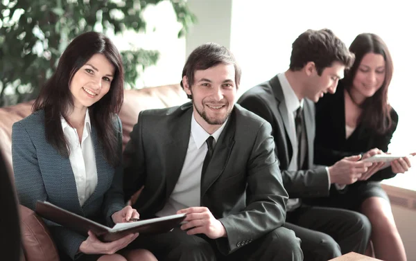 Close up.business coppia seduta nella hall dell'ufficio sullo sfondo dei colleghi — Foto Stock