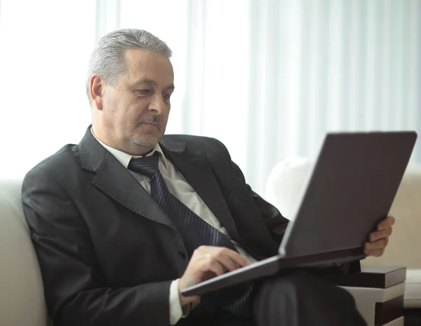 Επιτυχημένος επιχειρηματίας χρησιμοποιώντας φορητό υπολογιστή που κάθεται στο γραφείο υποδοχής — Φωτογραφία Αρχείου
