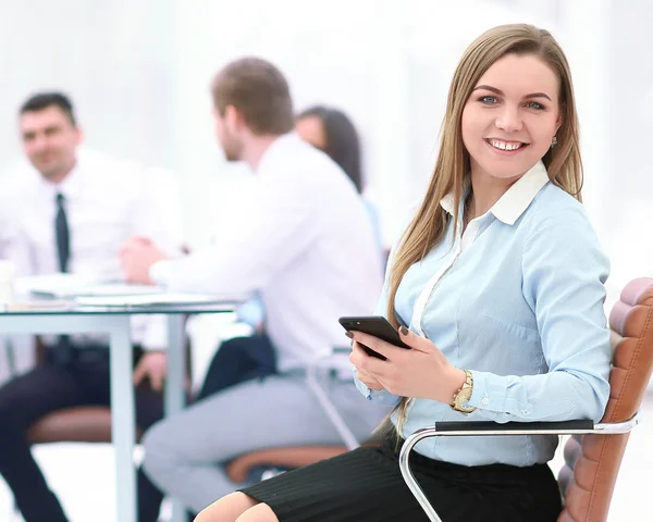 Ung anställd med en smartphone på bakgrunden av business-team — Stockfoto