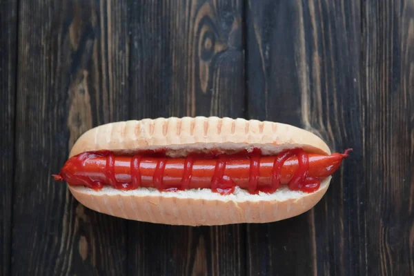Hot dog s klobásou na tmavé dřevěné background.photo s — Stock fotografie