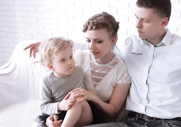 Familia feliz con la pequeña hija sentada en el sofá — Foto de Stock