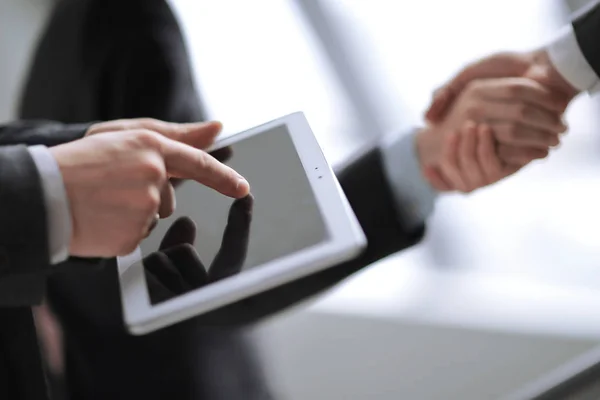 Close up.businessman using digital tablet on background of handshake of business partners — Stock Photo, Image
