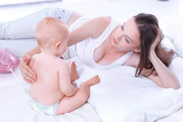 Gelukkig moeder praten met de baby liggend op het bed — Stockfoto