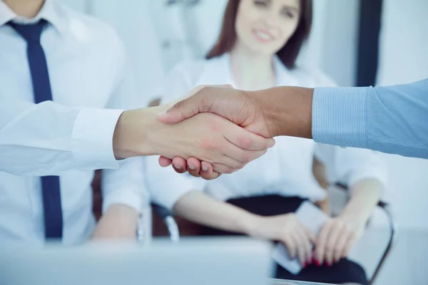 Closeup.Two hombres de negocios multiculturales apretón de manos sobre el escritorio. concepto de asociación —  Fotos de Stock