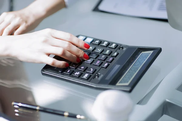 .closeup.Business kvinna använda en miniräknare på arbetsplatsen. — Stockfoto