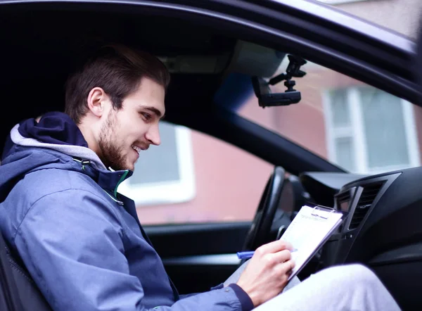 Człowiek podpisuje dokument siedząc w samochodzie — Zdjęcie stockowe