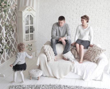 Genç Anne ve onların şirin küçük kızı gülümsüyor, küçük köpeğiyle evde kanepede oturan