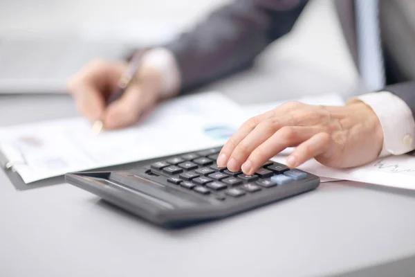 Z bliska. biznesmen wykorzystuje Kalkulator do sprawdzania sprawozdania finansowego — Zdjęcie stockowe