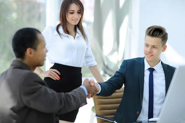 Handslag för affärspartners som sitter vid ett skrivbord — Stockfoto