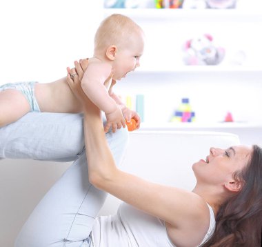 oturma odasında kanepede güzel bir bebekle oynayan genç anne