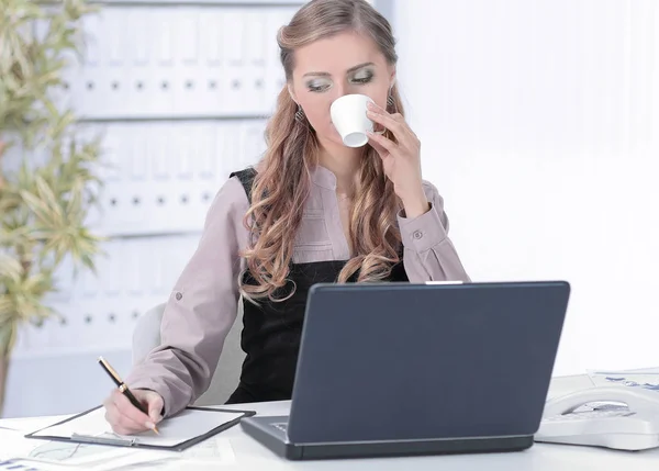 Jovem mulher de negócios com xícara de café no local de trabalho — Fotografia de Stock