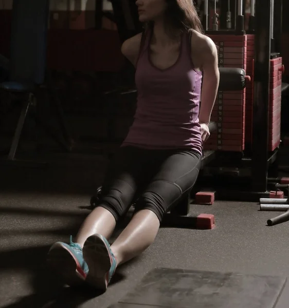 Sportliche Frau sitzt im Fitnesscenter auf dem Boden — Stockfoto