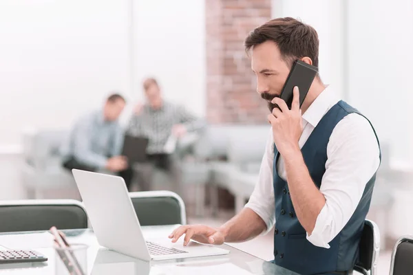 Empresário falando em um smartphone sentado em sua mesa — Fotografia de Stock