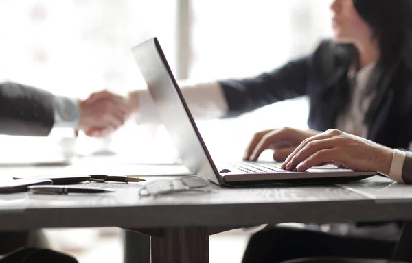 Affärsman som arbetar på laptop på bakgrunden av handslag av affärspartners — Stockfoto