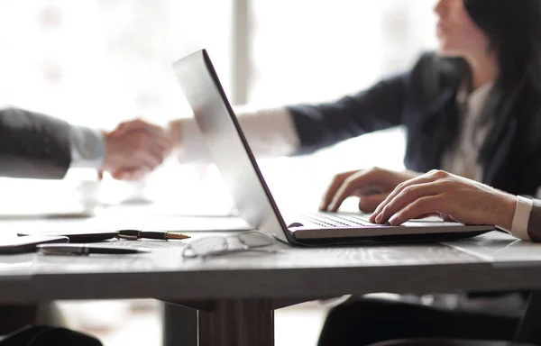 Businessman working on laptop on the background of handshake of business partners — Stock Photo, Image