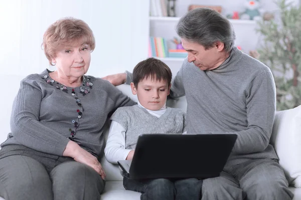 Babička, dědeček a vnuk při odpočinku na gauči při pohledu na obrazovku u notebooku — Stock fotografie