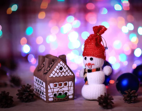 Speelgoed sneeuwpop en peperkoek huis aan de kersttafel — Stockfoto