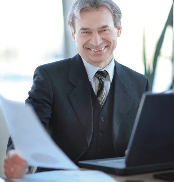 Lächelnder Geschäftsmann sitzt an seinem Schreibtisch — Stockfoto