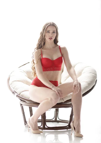 Schöne Frau in roter Unterwäsche sitzt in einem schicken Sessel — Stockfoto