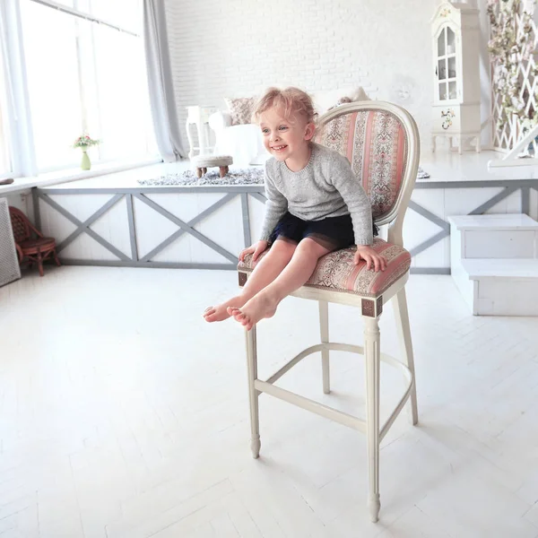 Retrato de niña feliz sentado en una silla en el amplio — Foto de Stock