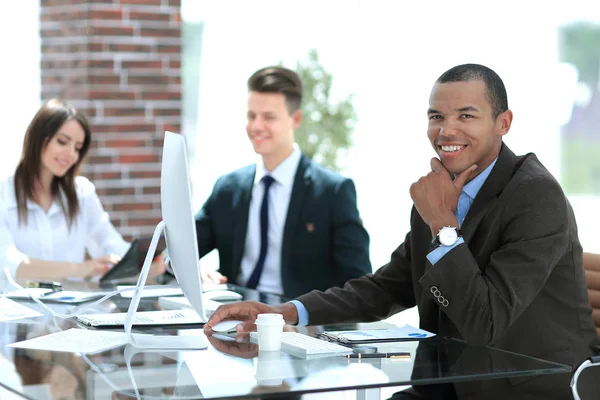 Joven hombre de negocios sentado detrás de un escritorio en una oficina moderna . — Foto de Stock