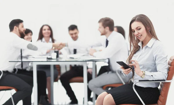 Joven empleado con un teléfono inteligente en el fondo del equipo de negocios — Foto de Stock