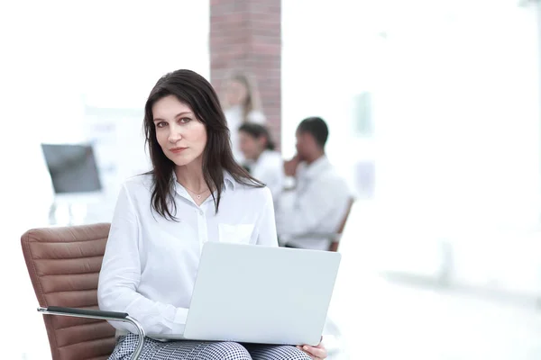 Mulher de negócios séria com laptop sentado no lobby do escritório — Fotografia de Stock