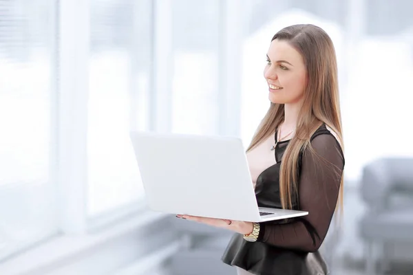 Joven mujer de negocios con portátil de pie en el vestíbulo de la oficina —  Fotos de Stock