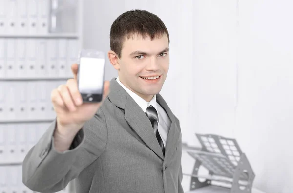 Mann zeigt Bildschirm des Smartphones, während er im Büro steht. — Stockfoto