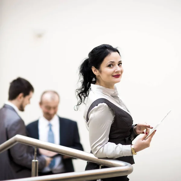 Modern businesswoman holding tablet computer with colleague on background — Stock Photo, Image