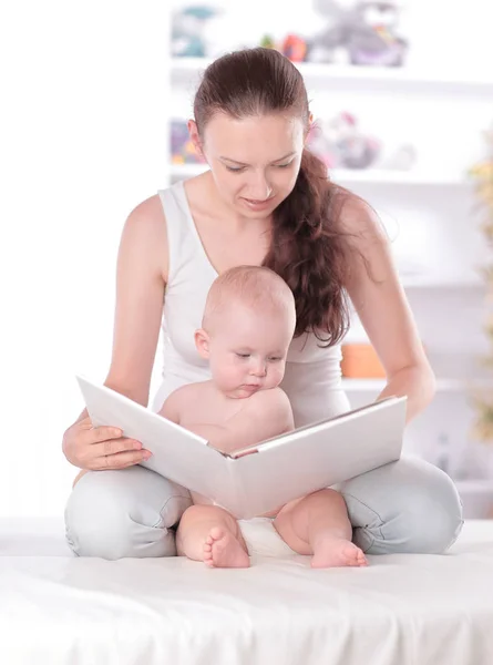 Genç anne küçük kızına bir kitap okuyor. — Stok fotoğraf
