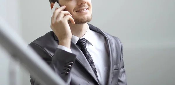 Close up.smiling businessman talking on smartphone in office — Stock Photo, Image