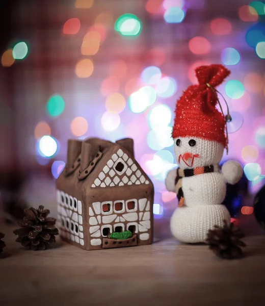 Speelgoed sneeuwpop en peperkoek huis aan de kersttafel — Stockfoto