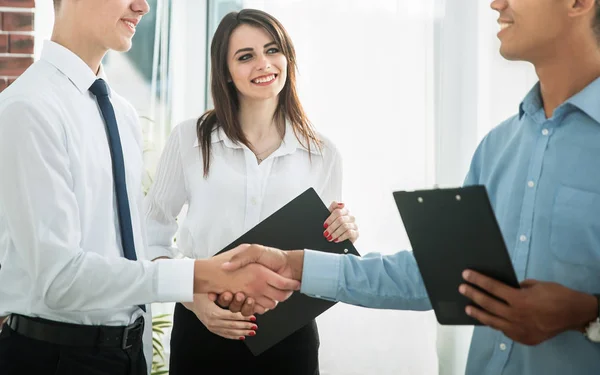 Apretón de manos de los socios comerciales jóvenes en la oficina — Foto de Stock