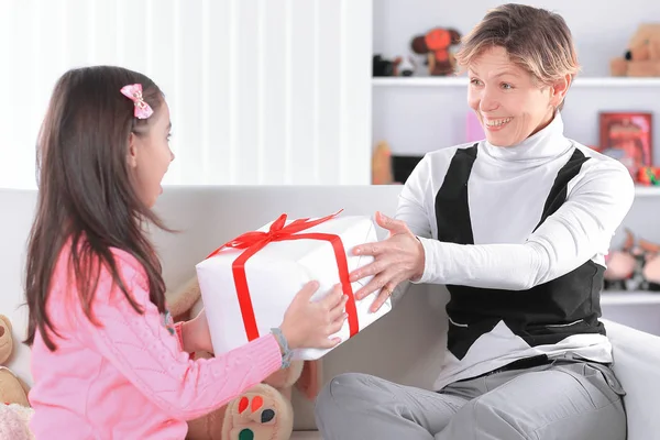 Abuela le da a su nieta una caja con un regalo — Foto de Stock